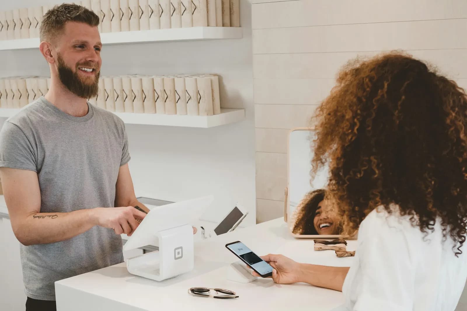 Cliente pagando con el celular en el mostrador de un comercio atendido por su dueño